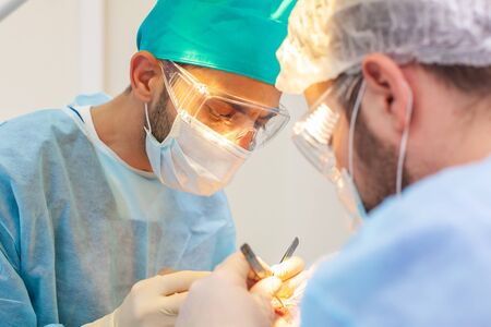 Baldness treatment. Hair transplant. Surgeons in the operating room carry out hair transplant surgery. Surgical technique that moves hair follicles from a part of the head.の写真素材