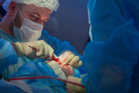 Surgeon and his assistant performing cosmetic surgery on nose in hospital operating room. Nose...