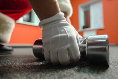 Santa Claus training at the gym on Christmas Day. Santa Claus is working out with dumbbells.の写真素材