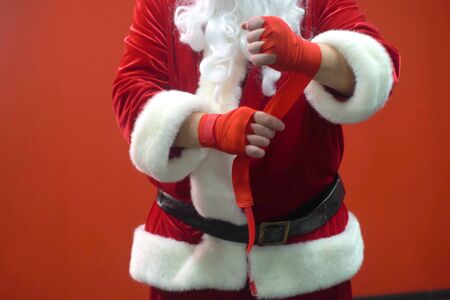 Santa Claus Fighter kickbox With Red Bandages against the background of a red wallの写真素材