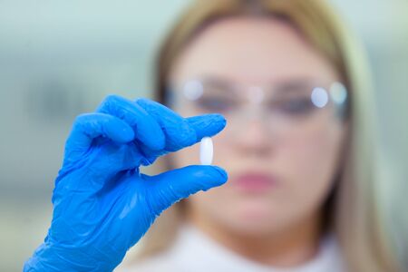 Technician holding a pill. Scientists create new drugs and vaccines in a modern scientific...