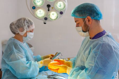 Hospital. Surgeon operates in the operating room. The doctor and nurse disinfect the implant before...