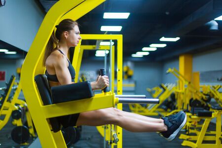 An athletic strong woman doing exercises for abdominal muscles at the parallel bars in a gym. Side view. ABS.の写真素材