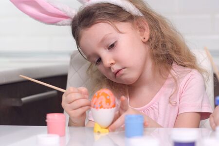 Happy easter. Little girl painting Easter eggs. Happy family children preparing for Easter. Cute little child girl wearing bunny ears on Easter day.の写真素材