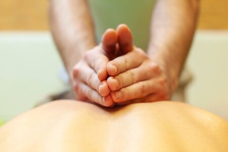 Close-up of massage therapist hands massaging his client back.の写真素材