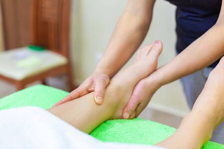 Close up photo of professional therapist hands giving relaxing reflexology Thai oil leg massage treatment to a woman in spa.の写真素材