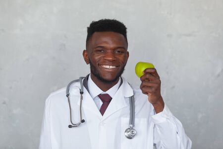 Black man doctor with green apple in the hand is ready to fight against the COVID, COVID-19, coronavirus, pandemic, epidemic, virus. Concept of humanitarian assistance to African countriesの写真素材