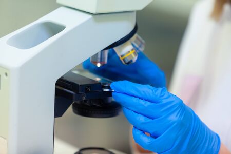 Close up of technicians hands in blue gloves changing samples in a microscope. COVID-19. COVID...