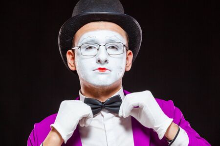 Portrait of male mime artist, isolated on black background. Close up of man face. Man adjusts his bow tieの写真素材