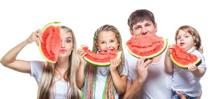 Portrait oh happy family with two kids holding watermelon slices in front of their faces isolated on white backgroundの写真素材