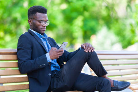 Young African entrepreneur is focused on work issues and communicating on a mobile phone for...