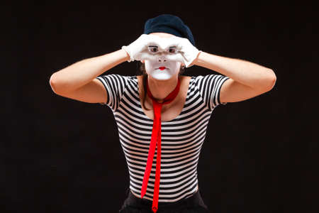 Portrait of male mime artist performing, isolated on black background. Man folds his hands as if...