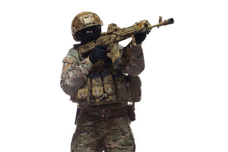 Side view of army man dressed in camouflage and full military equipment, wearing helmet, glasses and...