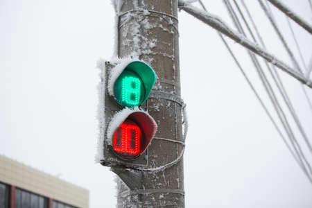 Shot of a frozen traffic light with blue sky and electrical wires in background. Increase in the number of accidents on an icy road in winterの写真素材