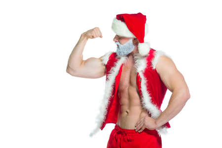 Christmas. Portrait of muscular sexy strong athlete in Santa Claus costume with grey beard posing showing his biceps isolated on white backgroundの写真素材