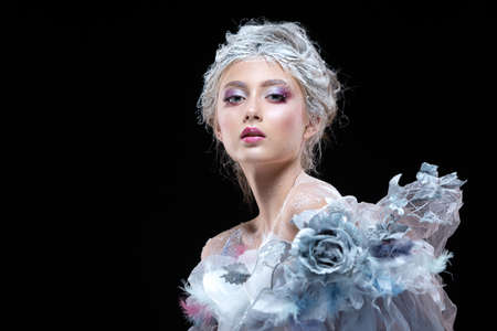 Winter Beauty Woman in clothes made of frozen flowers covered with frost, with snow on her face and shoulders. Christmas Girl Makeup. Make-up the snow Queen. Isolated on a black background.の写真素材