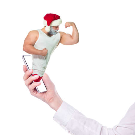 Christmas online fitness. Collage with muscular Santa Claus and smartphone in hand. The athlete...