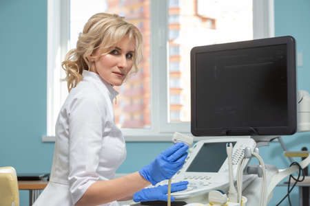 Photo of a beautiful female doctor sitting at an ultrasound diagnostic machine ready to receive...