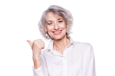 Close up portrait of a happy smiling mature woman in her sixties with trendy grey hair making thumbs...
