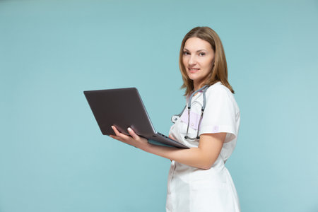 Beautiful female doctor with a stethoscope and a laptop, on a blue background. Online consultation. Copy paste. healthcare concept.の写真素材
