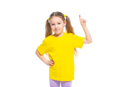 Little cute girl keeps pointing her finger at copy space. Isolated on white background.