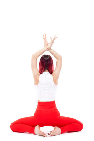A beautiful, athletic, slim, smiling and cheerful woman in a white top and red sweatpants performs stretching and Pilates elements. Lifestyle concept with sports and gym, healthy lifestyle. Isolated on white backgroundの写真素材