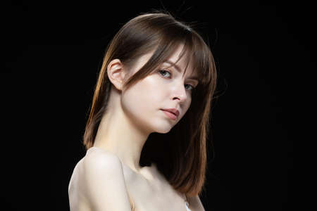 Close-up portrait of a young woman on a black background.の写真素材