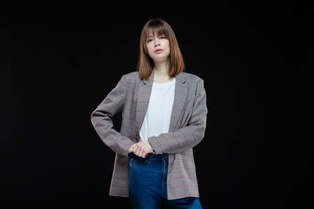 Portrait of a young modern business woman in a jacket on a black isolated background.の写真素材