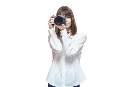Portrait of a young woman in a white shirt taking pictures with a camera. The concept of a successful photographer, wedding photographer, photo for documents. Isolated on white background.の写真素材