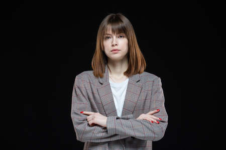 Portrait of a young modern business woman in a jacket on a black isolated background.の写真素材
