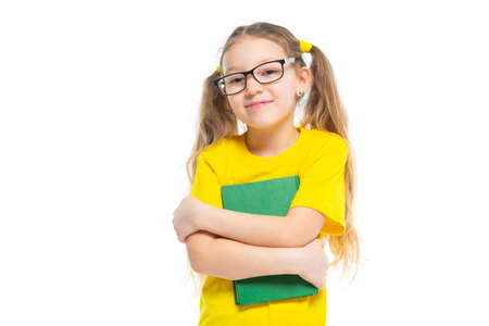 Cheerful young child girl with glasses holding a book to study isolated on a white background.