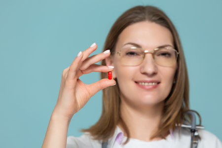 Woman doctor shows medication, on a blue background. Copy paste. healthcare concept.の写真素材