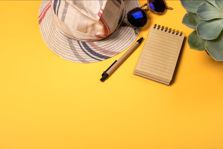 Colorful summer female fashion outfit flat-lay. Straw hat, sunglasses, cactus, notebook, pencil over yellow background, top view, copy space, square crop. Summer fashion, holiday concept. Punchy Pastelsの写真素材