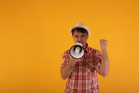 Portrait of a man with a megaphone on a yellow backgroundの写真素材