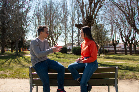 Couple of a mature man and a young woman, chatting and sharing their time, in a garden on a sunny dayの写真素材