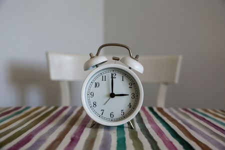 White table bell alarm clock on a colored striped base