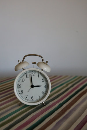 White table bell alarm clock on a colored striped base