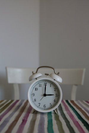 White table bell alarm clock on a colored striped baseの写真素材