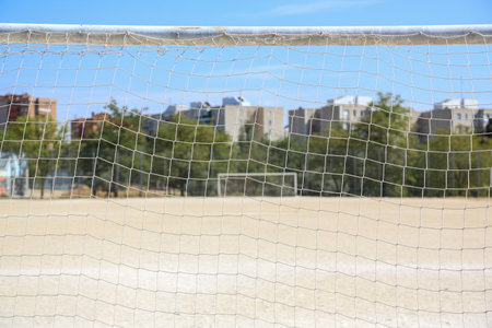 A dirt soccer field. You can see the white lines, the goalposts, their nets, and the gate closed...