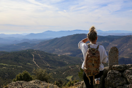 Blonde woman with a bun looking at the mountains after walking along the paths accompanied by her...