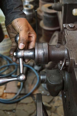 Closeup of a hand crank with mechanics closely operating the machine, scale of old Lathe Machinery. Vintage Industrial Machinery in a old factory.の写真素材