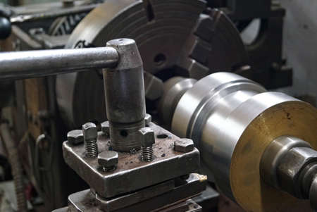 Closeup of a metal shaft parts cutting by old Lathe Machinery. lathe chuck and key 4-jaw screw chuck. Vintage Industrial Machinery in a old factory.の写真素材