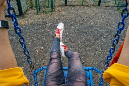 A boy sitting and using playground swing set at mountain village Kalakund near Mhow, Indore, Madhya Pradesh on a sunny summer day. Indian village.の写真素材