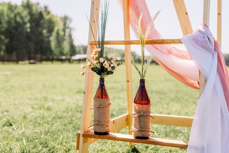 The chairs and table for guests, decorated with candle and floral arrangement, served with cutlery, crockery. Wedding banquet on a green lawn in the field, on the territory of the stable. Deer farm.のeditorial素材