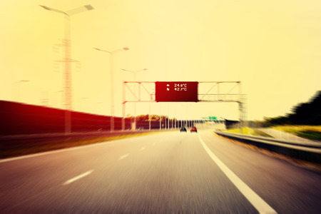 A Highway With Traffic on a Bright And Sunny Day. The Digital Temperature Indicator Shows the High...
