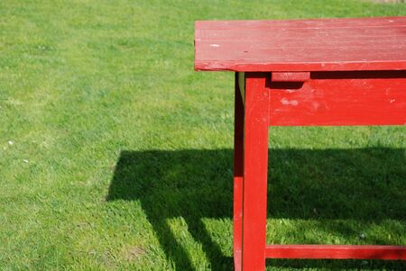 self made table of planks coloured red standing on the green grassの写真素材