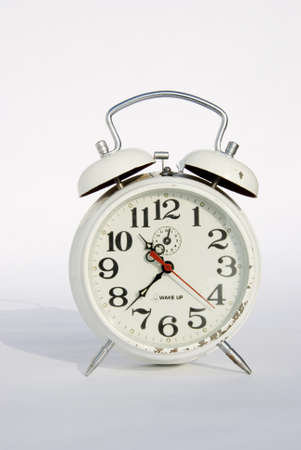 Old white mechanical alarm clock on a white background
