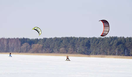 Kiteboarding with snowboards on frozen lake in winter. Active and modern people leisure. のeditorial素材