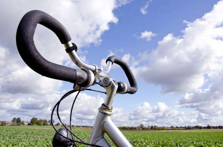 Bicycle handlebar closeup on background of blue cloudy sky. Vehicle does not require fuel. Active healthy people transportation. の写真素材