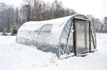 wooden diy homemade greenhouse covered with polythene and snow in winter  